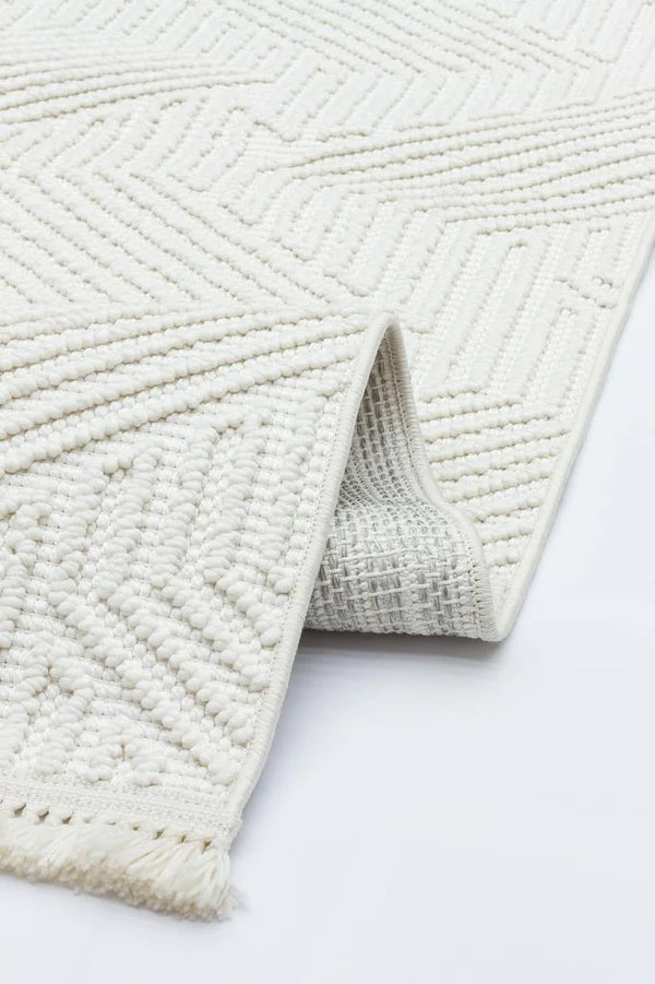 Beyaz geometrik desenli kabartmalı dokuma pamuk halı, kenarında püskül detayı