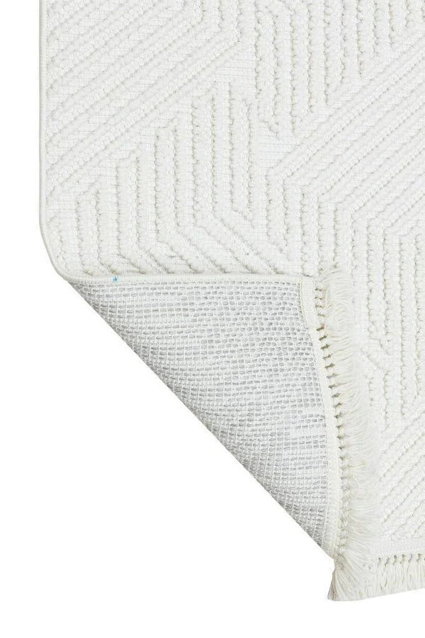 Beyaz geometrik desenli dokuma ve püsküllü modern dekoratif halı köşesi