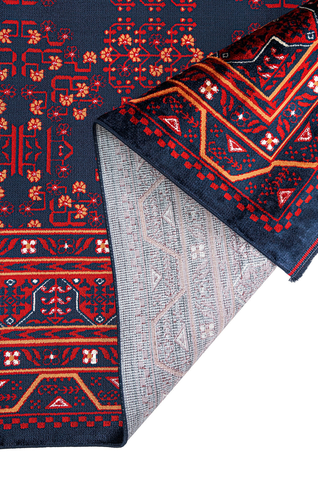 Koyu lacivert ve kırmızı geleneksel desenli halının kenarı kıvrılmış detaylı görünüm