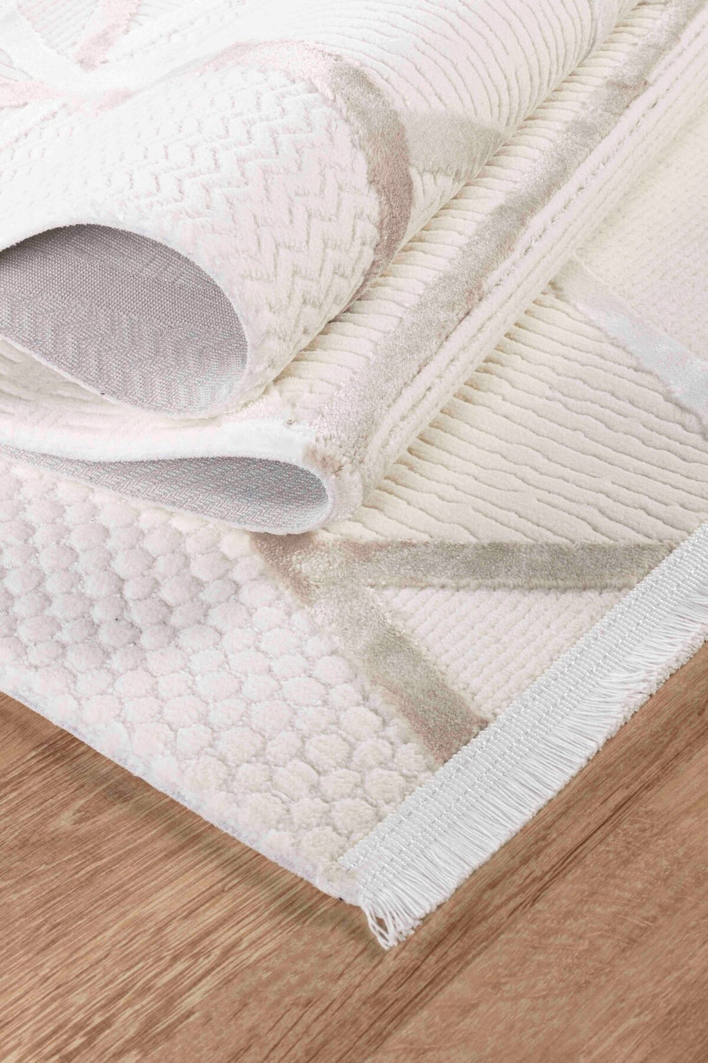 Krem rengi desenli dokulu halı, ahşap zemin üzerinde kıvrılmış şekilde