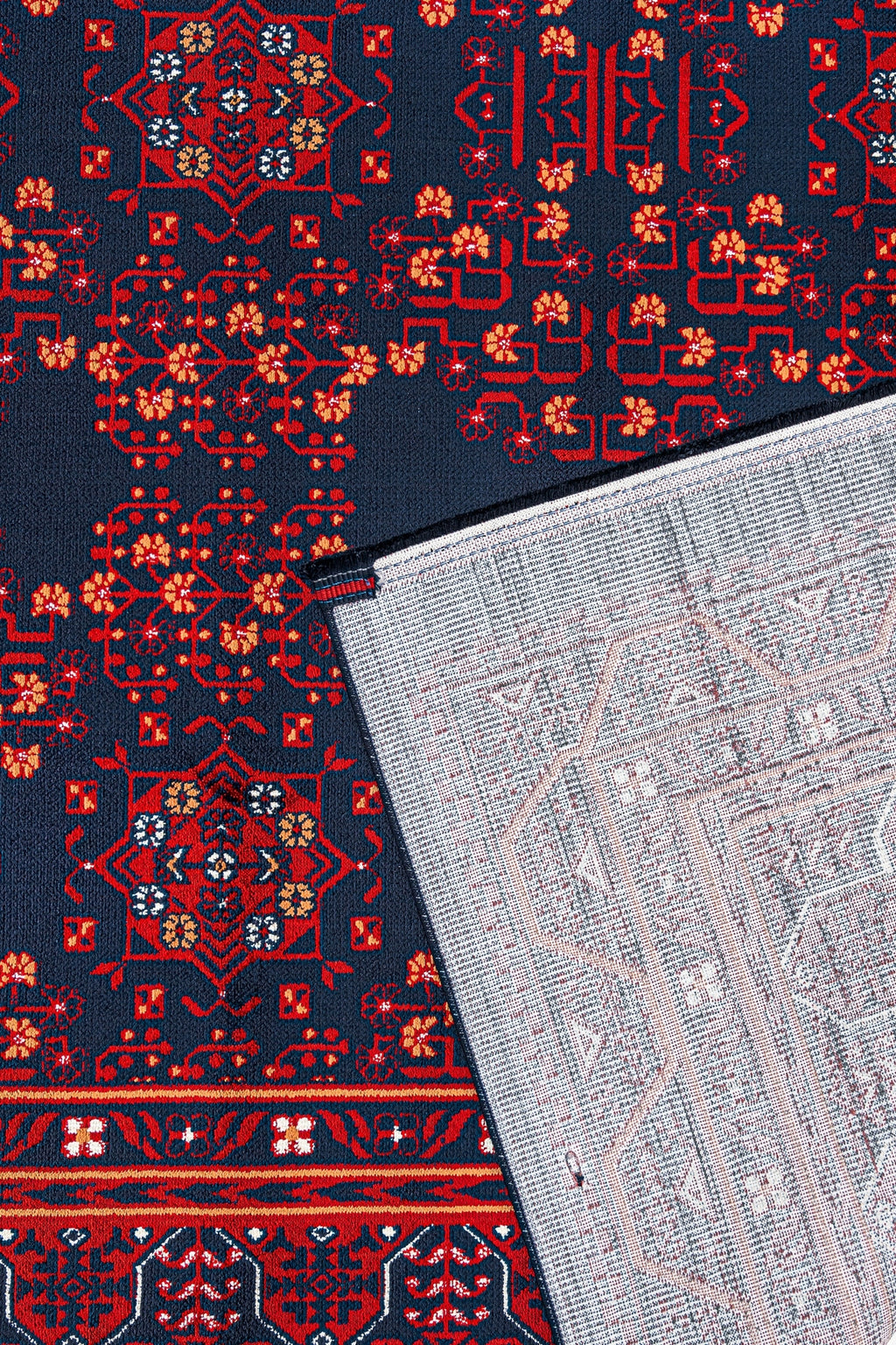 Kırmızı ve lacivert renkli işlemeli geleneksel halı, köşesi ters çevrilmiş ve desenli