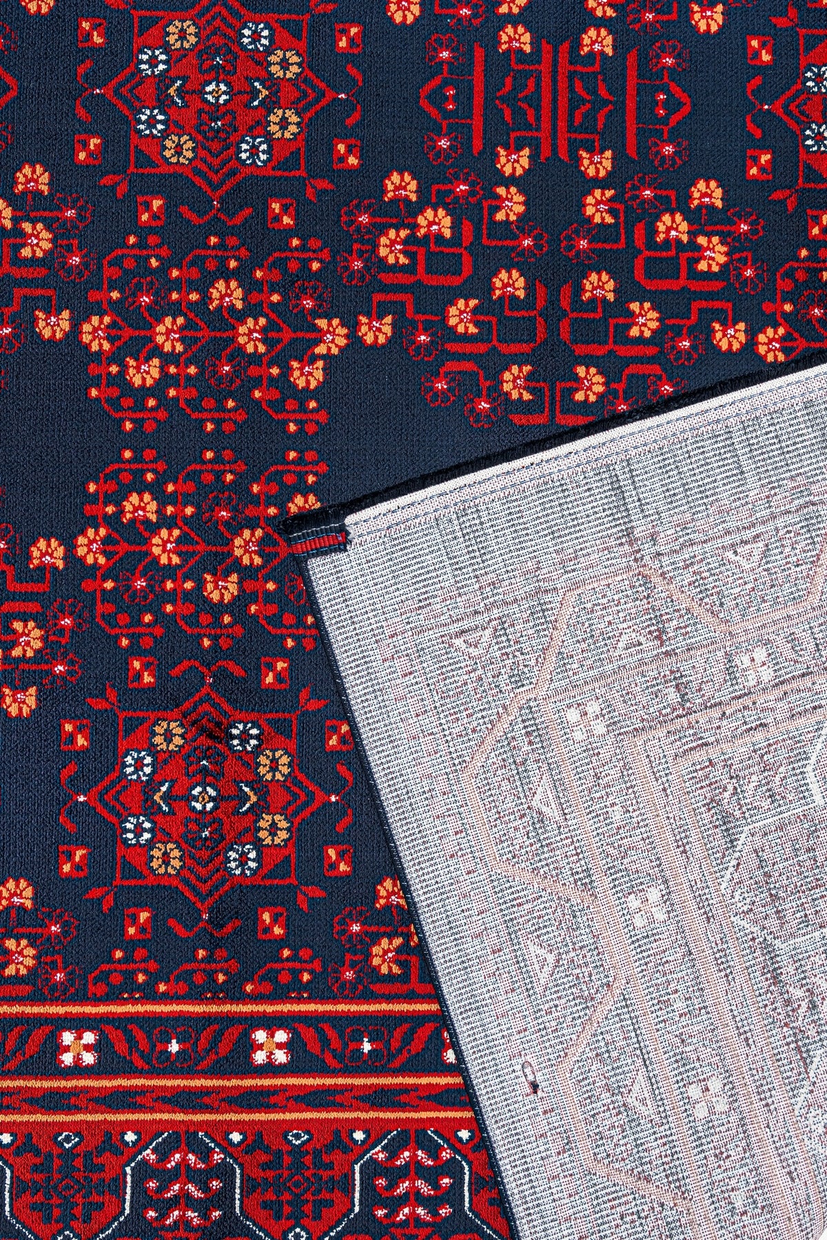 Kırmızı ve lacivert renkli işlemeli geleneksel halı, köşesi ters çevrilmiş ve desenli