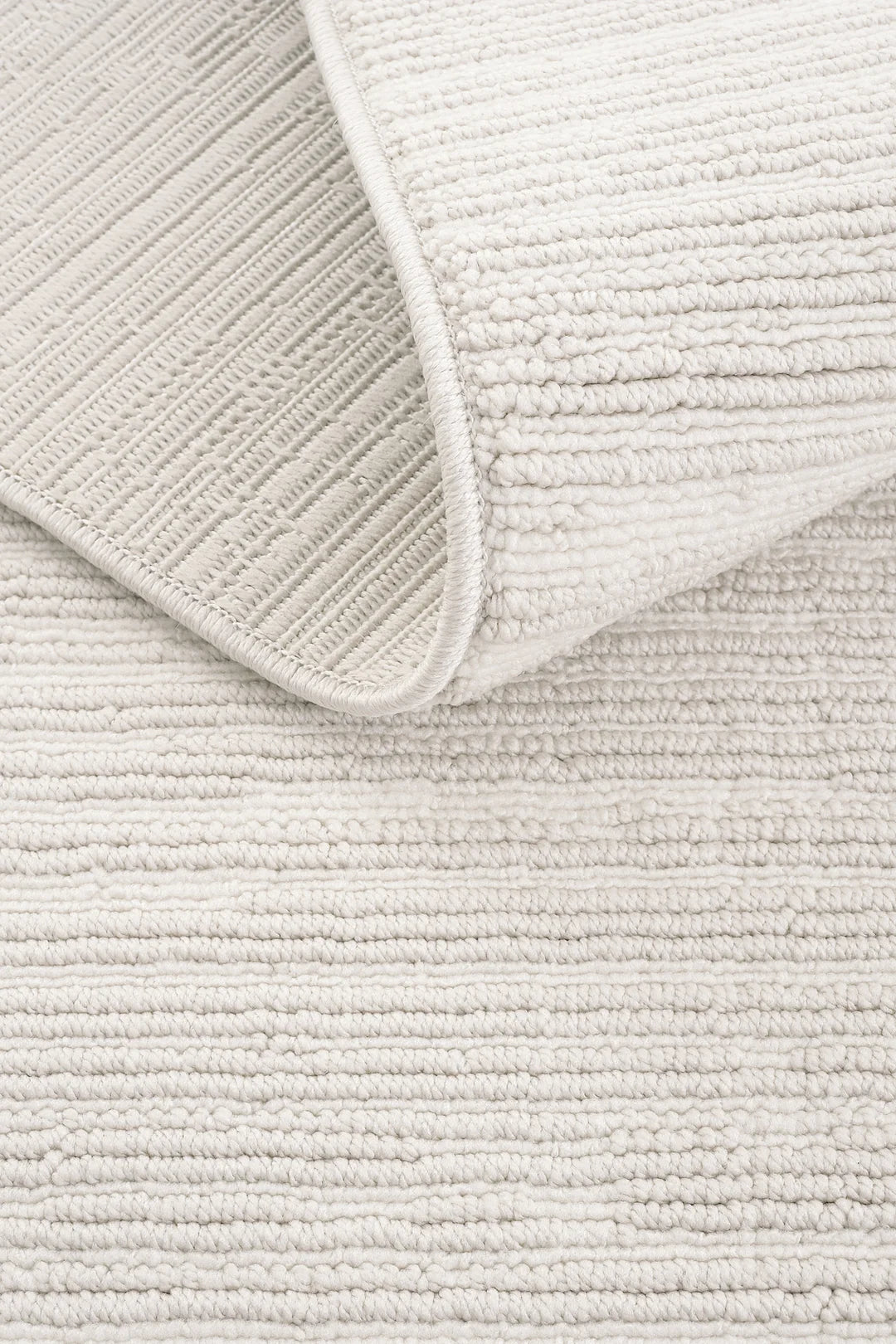 Beyaz tüylü dokulu modern halı ve ters çevrilmiş köşesi