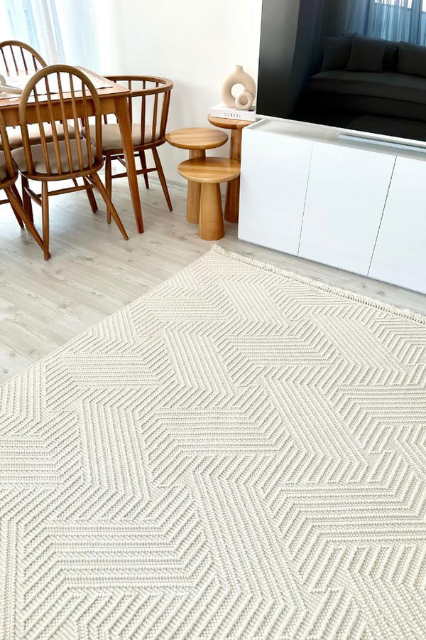 Geometrik desenli krem halı, ahşap yemek masası ve sandalyeler, beyaz TV ünitesi modern oturma odası