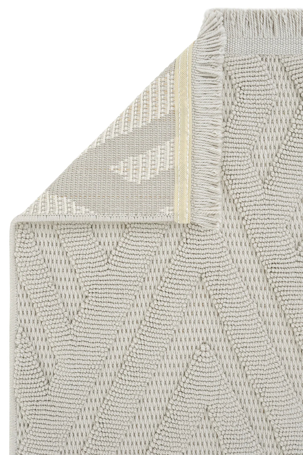 Açık gri ve beyaz geometrik desenli dokuma kilim, köşesi katlanmış ve püsküllü kenar detaylı
