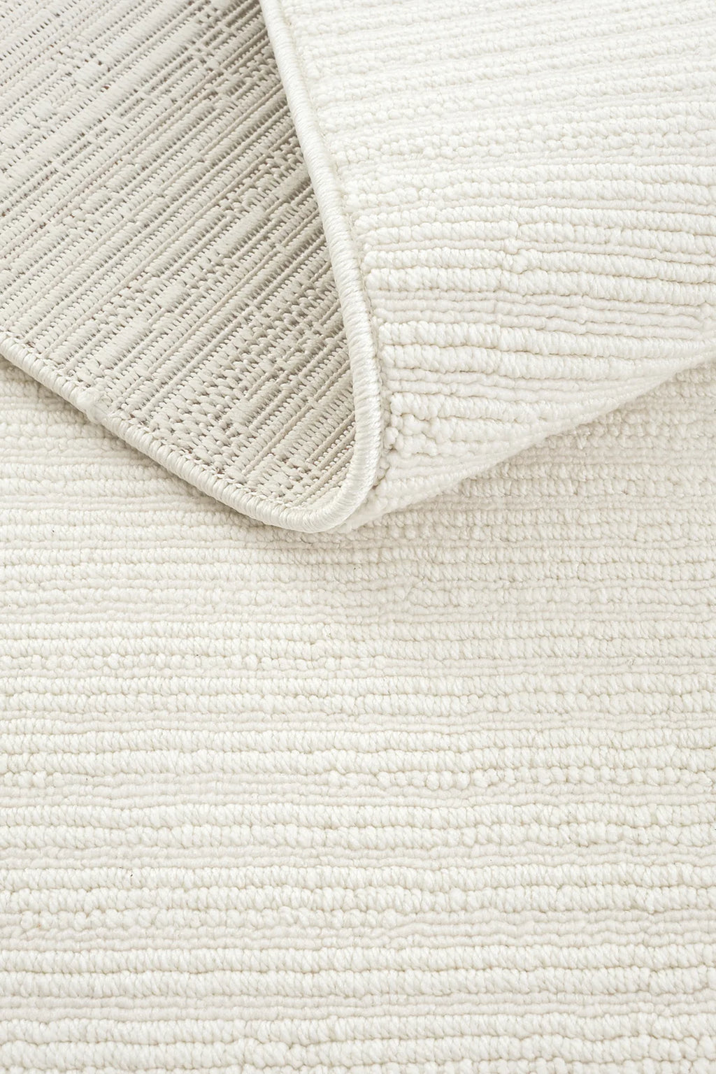 Beyaz dokulu yumuşak modern halı, kıvrılmış köşesiyle yer döşemesi