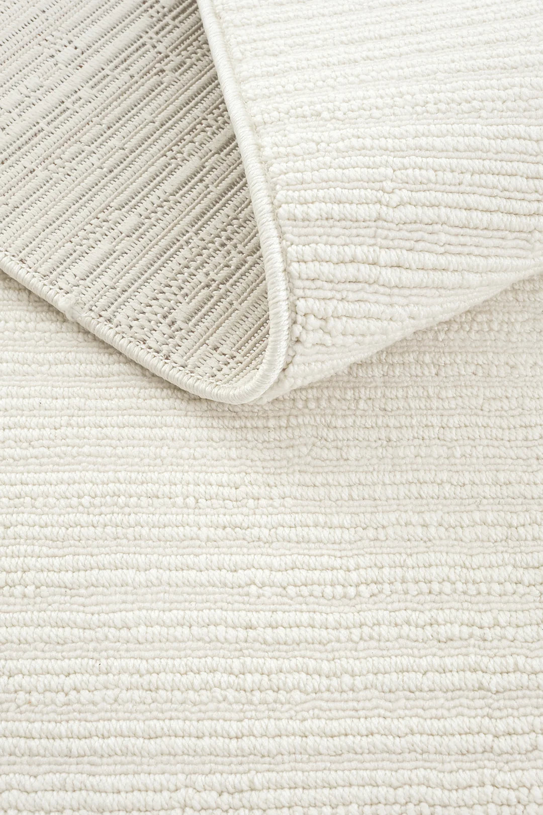 Beyaz dokulu yumuşak modern halı, kıvrılmış köşesiyle yer döşemesi