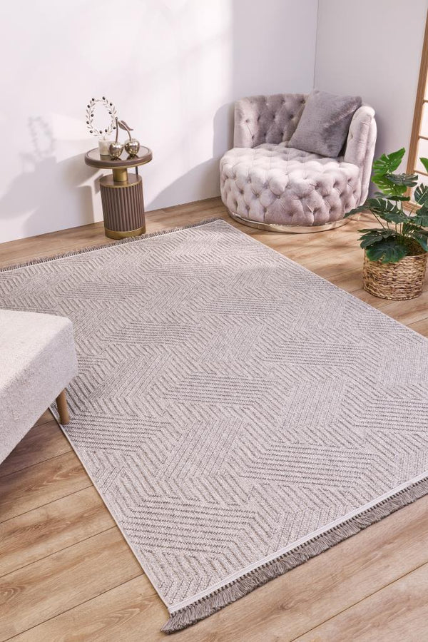 Modern açık gri desenli halı, yuvarlak tufted koltuk, ahşap zemin ve bitkili şık oturma alanı