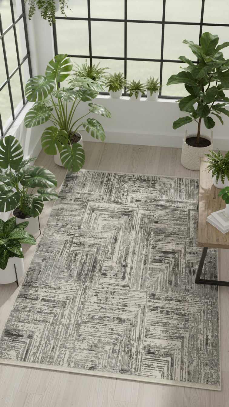 Modern gri geometrik desenli halı, salon köşesinde geniş pencere ve yeşil ev bitkileri ile
