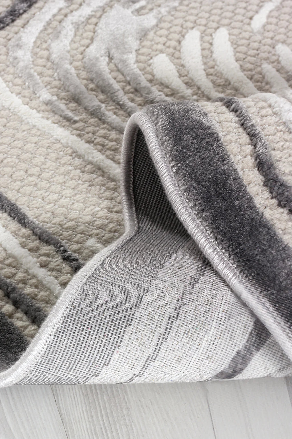 Krem ve gri tonlarında yumuşak dokulu modern desenli makine halısı köşesi açılmış