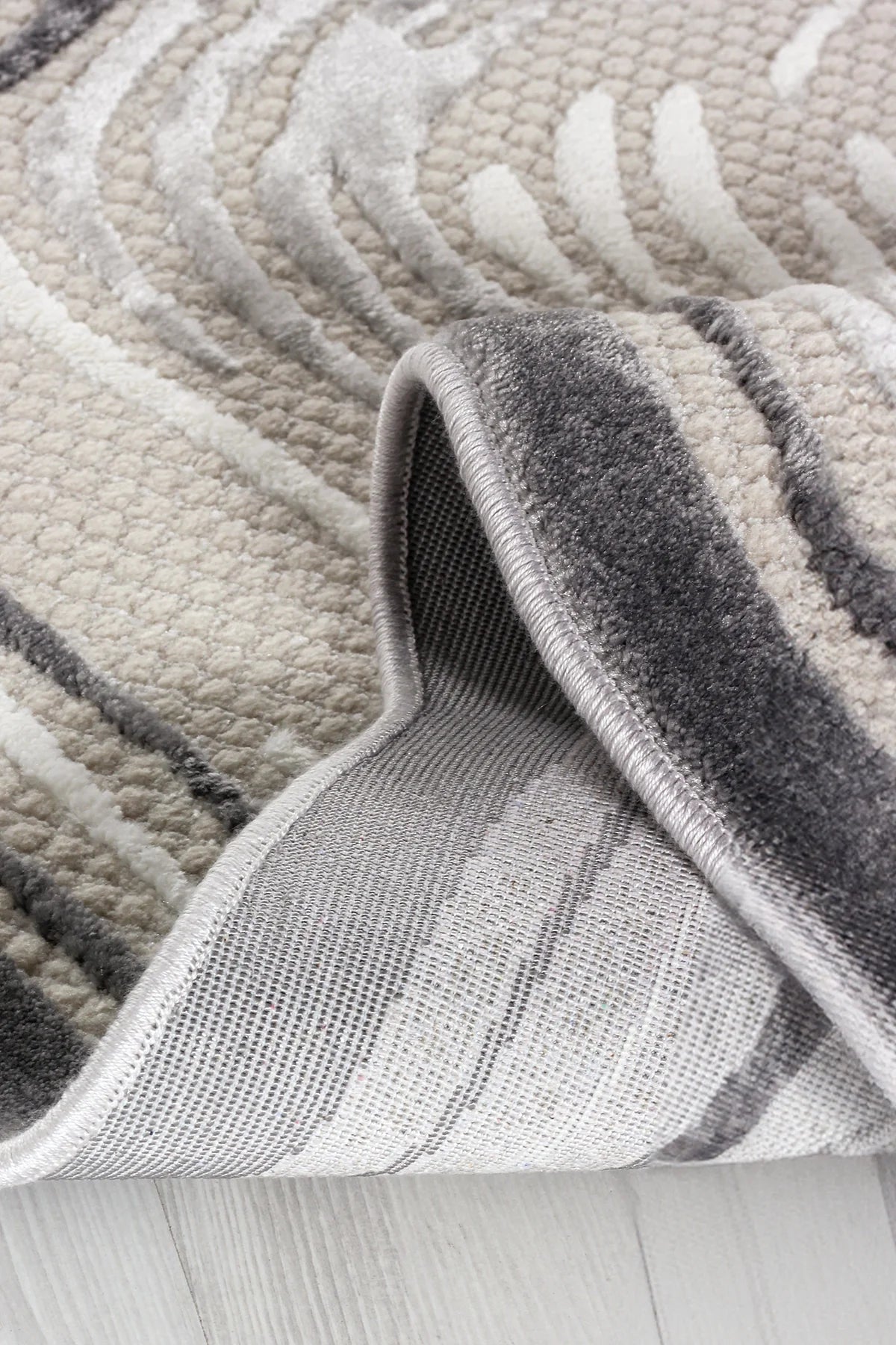 Krem ve gri tonlarında yumuşak dokulu modern desenli makine halısı köşesi açılmış