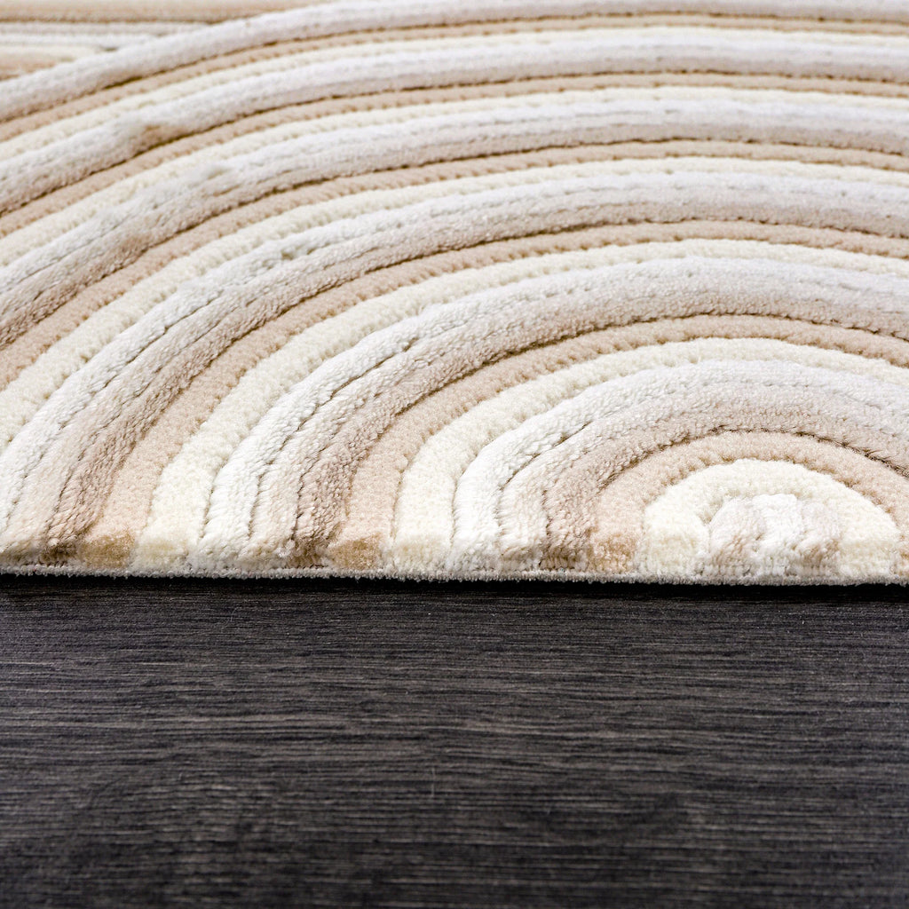 Krem ve kahve tonlarında dalga desenli yumuşak dokulu halı, koyu ahşap zemin üzerinde