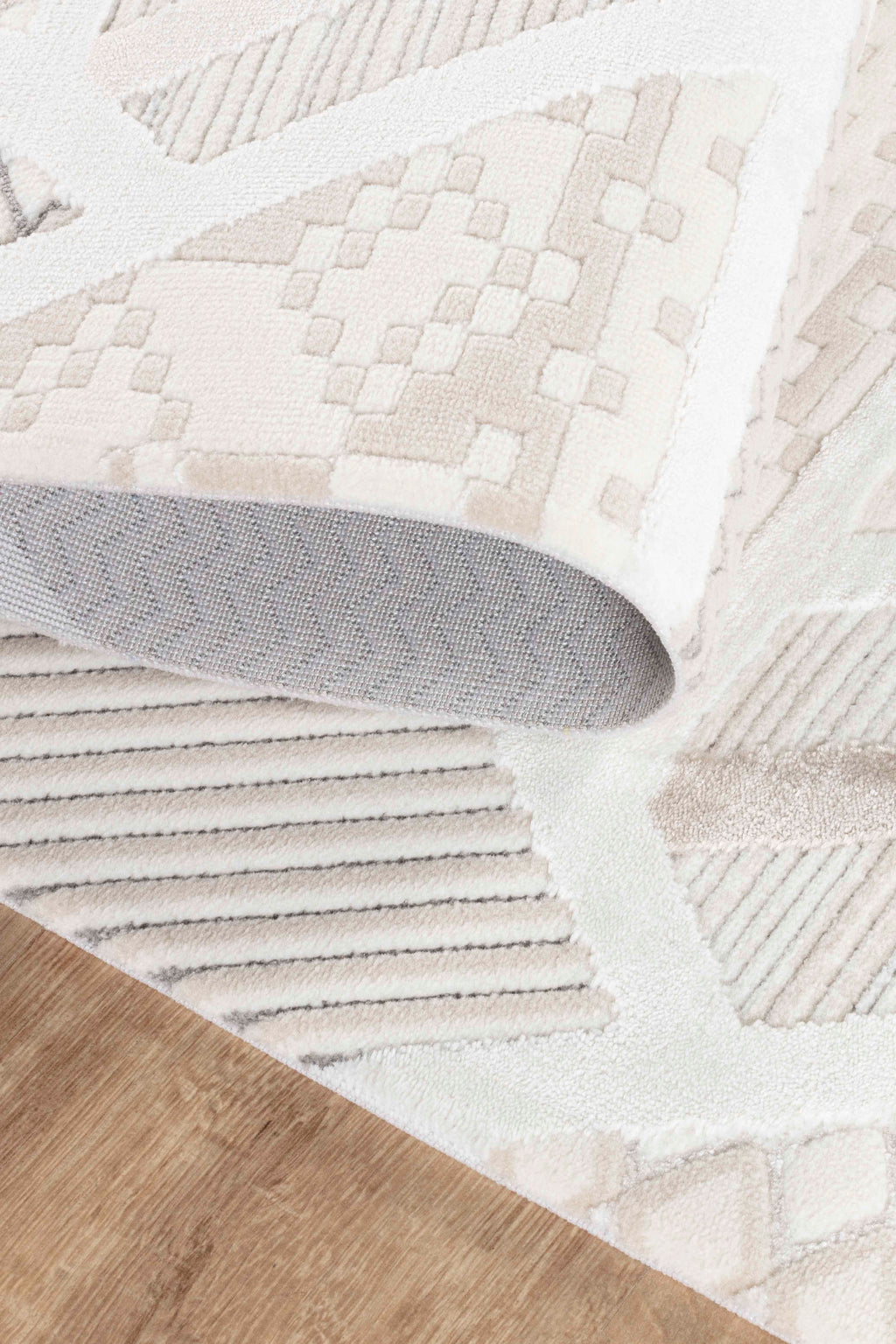 Krem ve kahverengi tonlarında desenli yumuşak dokulu makine halısı, ahşap zemin üzerinde