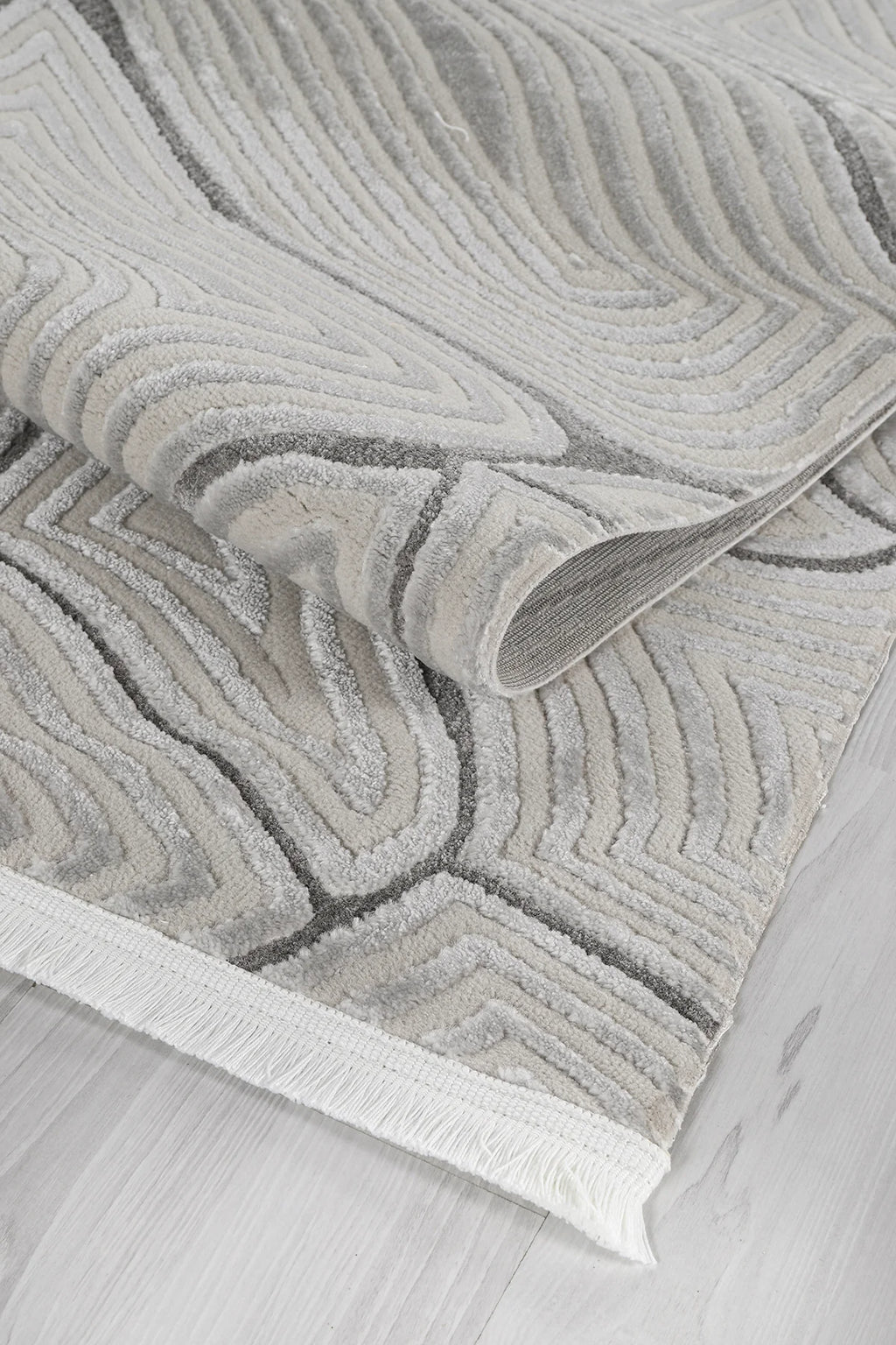 Gri ve beyaz tonlarda, kabartmalı geometrik desenli yumuşak dokulu salon halısı