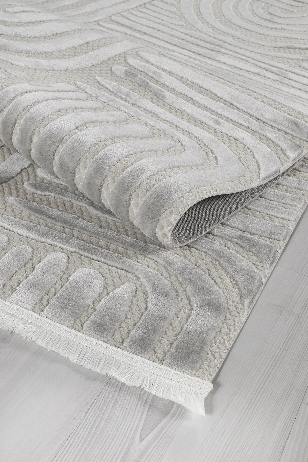 Yumuşak dokulu gri ve beyaz geometrik desenli makine halısı, açık renk ahşap zemin üzerinde