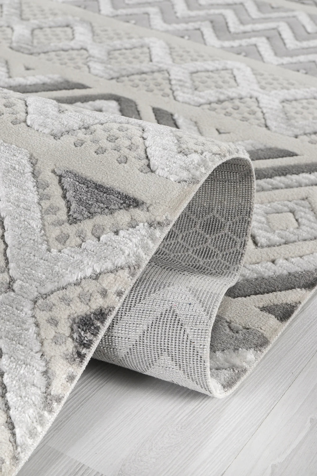 Gri ve beyaz renklerde geometrik desenli yumuşak dokulu şönil halı detayı