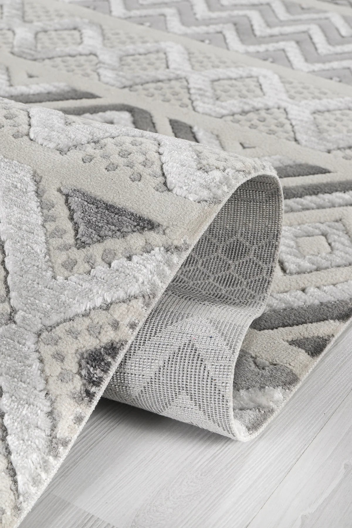 Gri ve beyaz renklerde geometrik desenli yumuşak dokulu şönil halı detayı