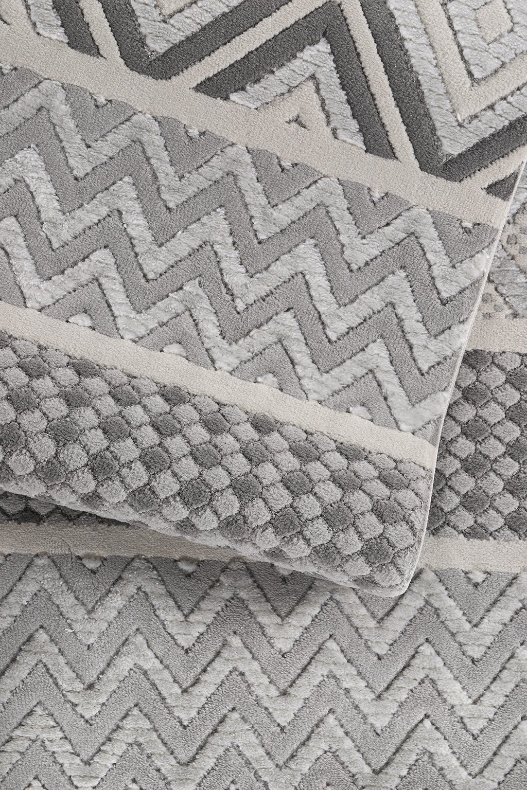 Gri ve beyaz zigzag ve noktalı desenli yumuşak dokulu makine halısı detay görüntüsü