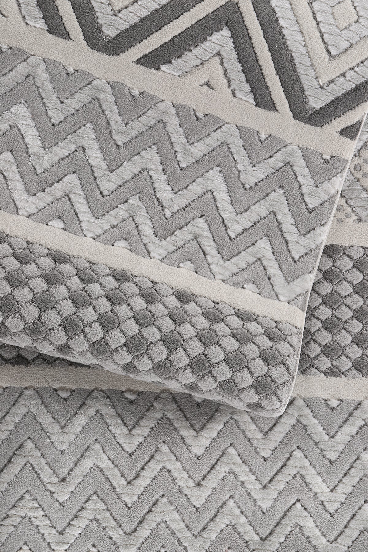 Gri ve beyaz zigzag ve noktalı desenli yumuşak dokulu makine halısı detay görüntüsü