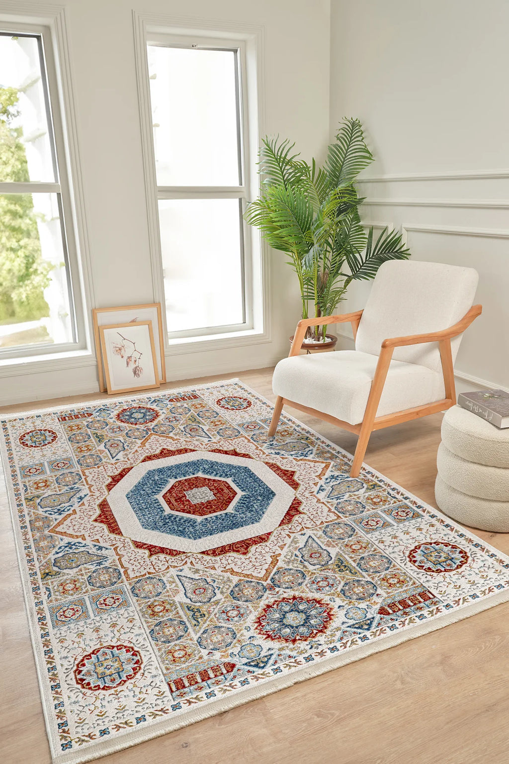 Renkli geometrik desenli salon halısı, ahşap detaylı beyaz koltuk ve büyük yeşil bitki