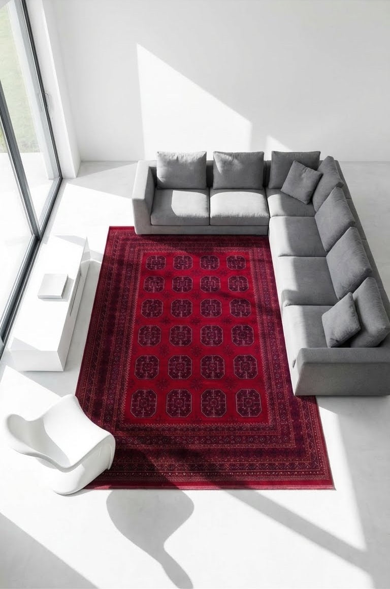 Modern gri L-koltuk ve beyaz sandalye üzerinde koyu kırmızı Afgan halı, bol doğal ışık alan minimal salon