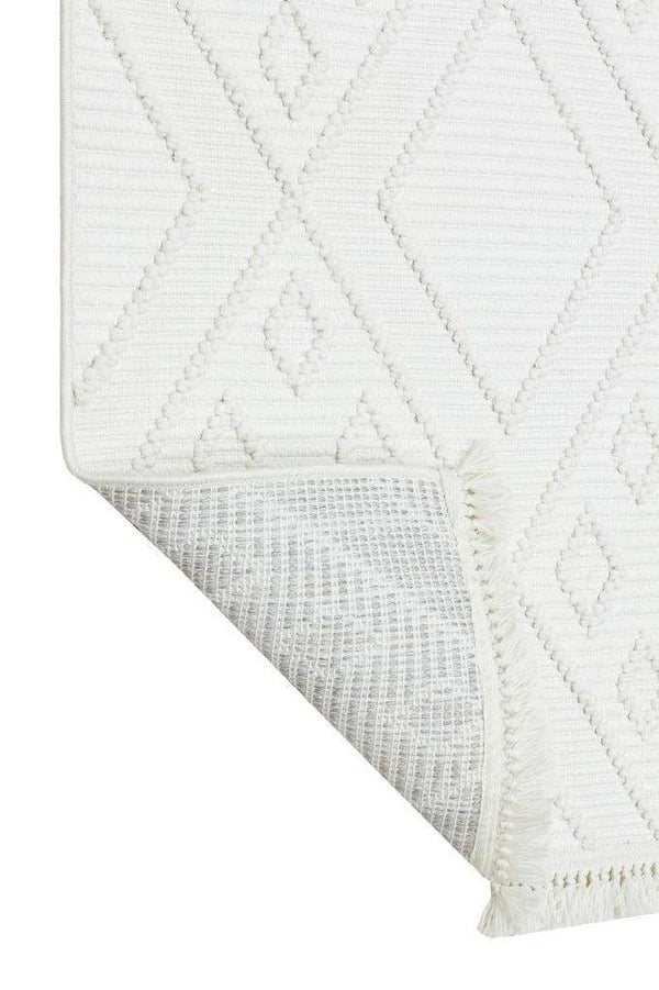 Ekru renkli, geometrik desenli makine dokuma halı köşesi, kısa püsküller ve dayanıklı dokuma