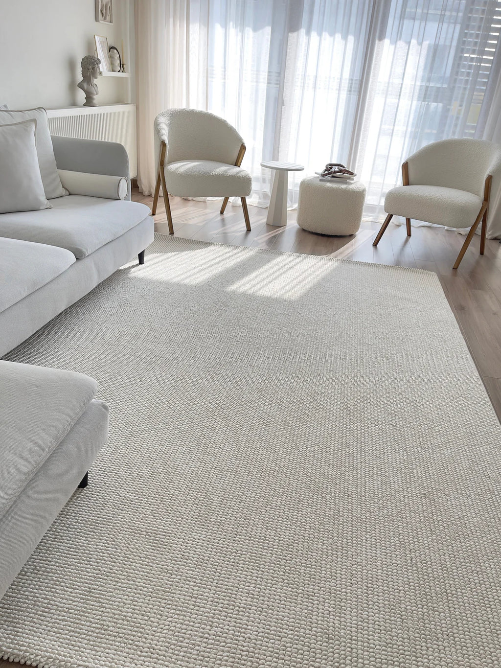 Ekru renk makine halısı, modern beyaz koltuk ve detaylı peluş berjerlerle aydınlık salon dekoru