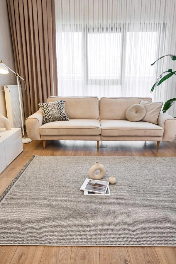 Bej modern koltuk, gri makine halısı, dekoratif yastıklar ve ahşap zeminli şık oturma odası