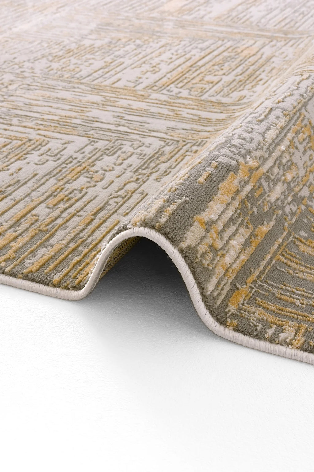 Gri ve altın renk tonlarında modern desenli kıvrımlı halı kenarı detayı