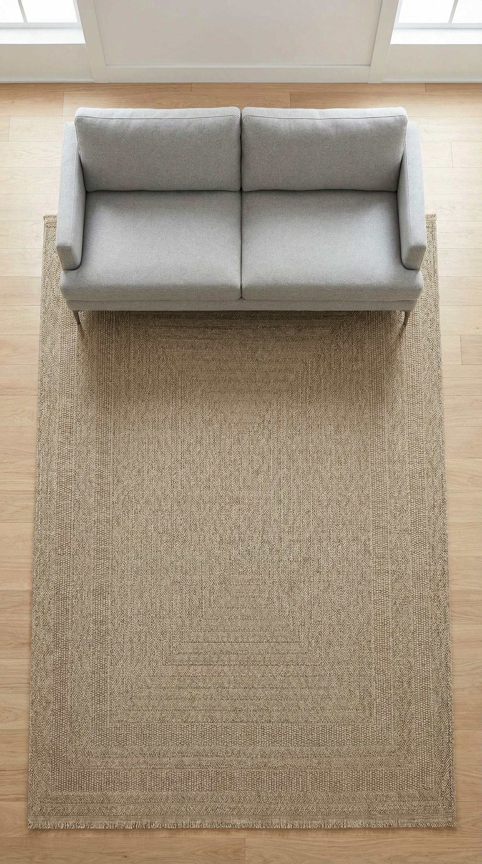 Ahşap zemin üzerinde doğal renk ve dokulu modern halı, üstünde gri iki kişilik kanepe