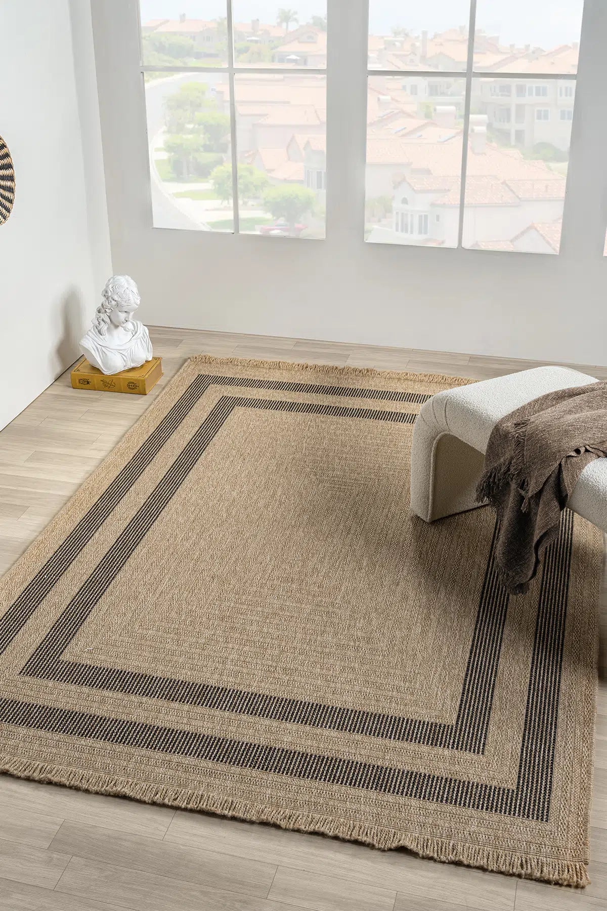 Siyah çizgili doğal iplikli kahverengi halı ve yanında beyaz oturma bankı, açık odada