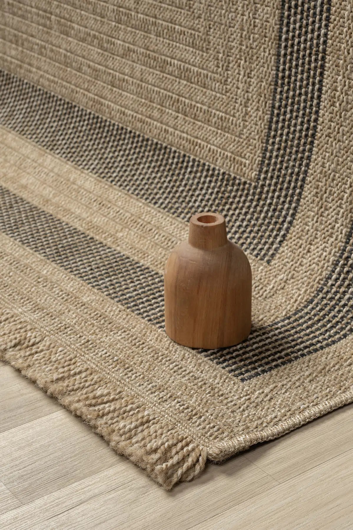 Doğal renklerde, siyah çizgili seyran halı ve ahşap dekoratif obje