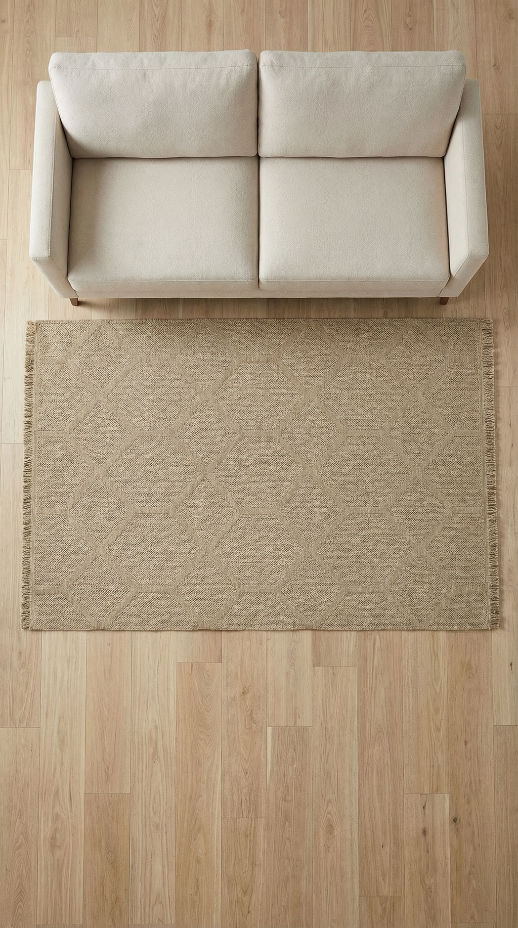 Bej renkli kanvas kumaş 2 kişilik kanepe ve altında desenli doğal jüt halı, açık ahşap parke zemin